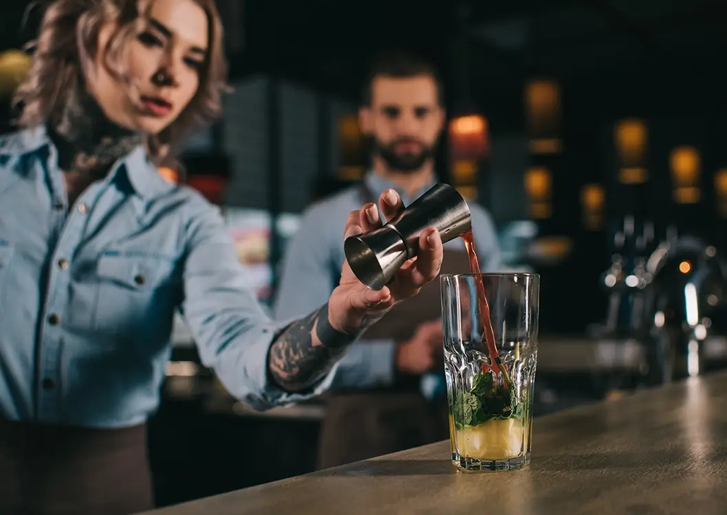 bartender adding ingredient to alcoholic drink at the bar