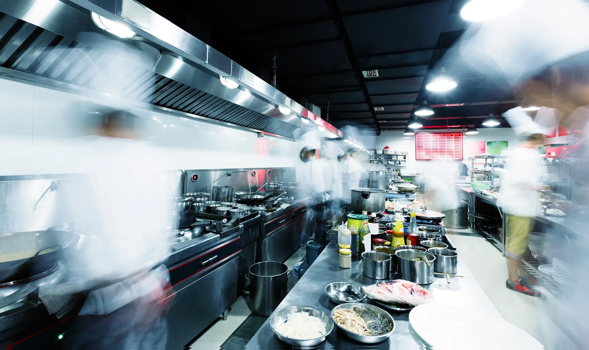 busy commercial kitchen with blurred images of chefs in white