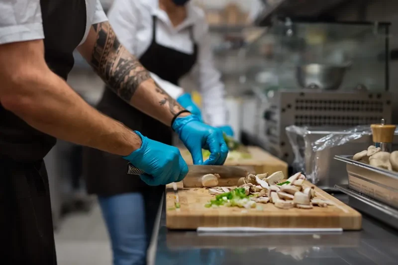 gloved hands of chef chopping mushrooms