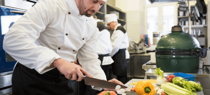 Chef with a knife chopping vegetables on a table