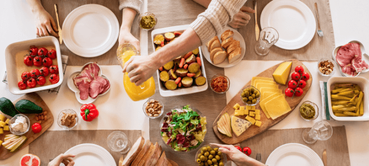 Woman pouring juice into a glass on a table neatly set with plates and dinner foods